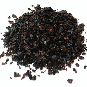 May include: A pile of black and brown dried black peppercorns. The peppercorns are small and irregularly shaped.