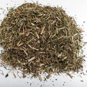 May include: A pile of dried, green and brown herbs. The herbs are finely chopped and look like they could be used for tea or cooking.