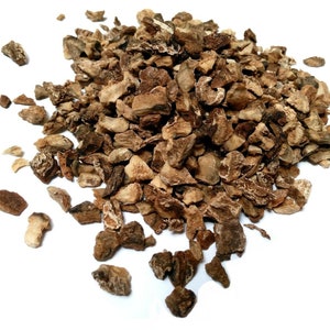 Pode incluir: Um monte de pedaços de raiz de bardana seca. Os pedaços são marrons e têm uma textura áspera.