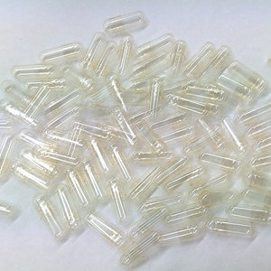 Puede incluir: Un montón de cápsulas de gelatina vacías y transparentes, comúnmente utilizadas para suplementos dietéticos o medicamentos.