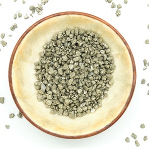 May include: A wooden bowl filled with small, rough, gold-coloured pyrite crystals. The bowl is on a white background.