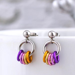 May include: A pair of silver stud earrings with a dangling hoop and four colourful rings. The rings are purple, pink, orange and yellow.