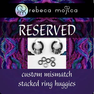 May include: Black and silver stacked ring huggie earrings. The earrings have a black hoop with multiple silver rings hanging from the bottom. The word "RESERVED" is in white text. The text "custom mismatch stacked ring huggies" is also present.