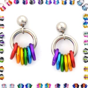 May include: A pair of silver-toned earrings with a large ring design. Each earring features a rainbow of colored rings hanging below the main ring. The earrings are surrounded by other colorful ring designs.