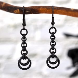 May include: Black dangle earrings with a chain of linked rings and a double ring at the bottom.