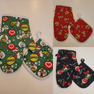 May include: Three sets of oven mitts and pot holders with Christmas-themed designs. One set is green with Grinch and ornament patterns, another is red with Grinch and star patterns, and the last is black with Grinch and bow patterns.