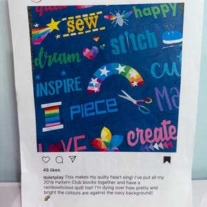 May include: A navy blue quilt top featuring colorful appliqued designs including a rainbow, scissors, a spool of thread, and text such as sew, stitch, dream, inspire, piece, and create. The quilt is displayed within a printed social media frame.