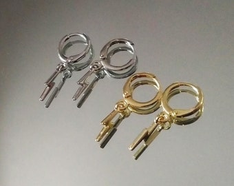 Op de afbeelding: Twee paar oorbellen met bliksem-charms. Het ene paar is zilver en het andere is goud.