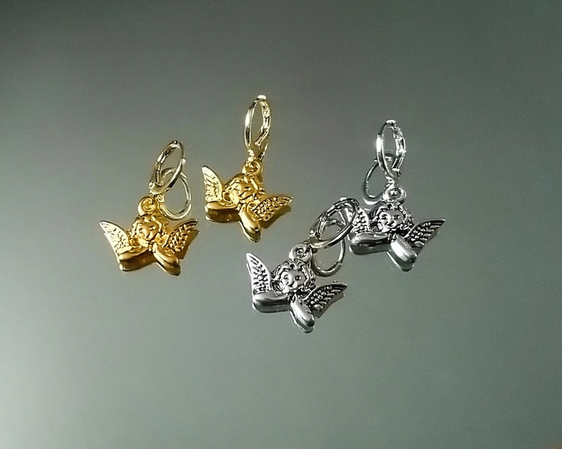 May include: Three pairs of angel charm earrings. One pair is gold, one is silver, and one is a mix of gold and silver.