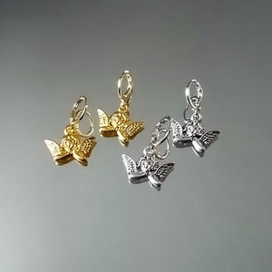 May include: Two pairs of angel charm earrings. One pair is gold and the other is silver.