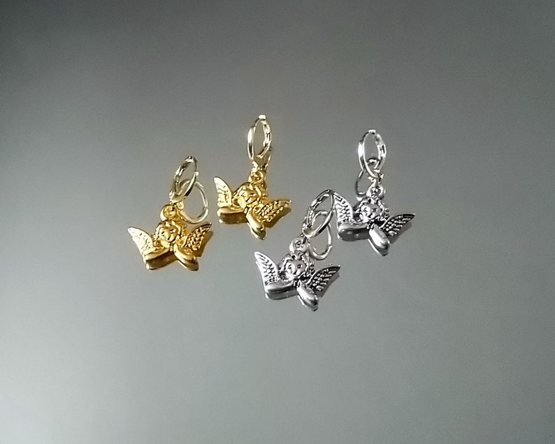 May include: Two pairs of angel charm earrings. One pair is gold and the other is silver.