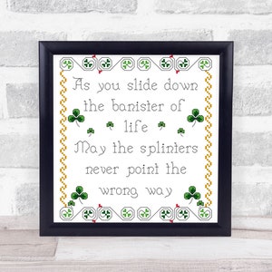 May include: A framed cross-stitch design with a white background and green shamrocks. The text reads: "As you slide down the banister of life, may the splinters never point the wrong way."