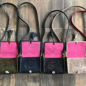 May include: Five small leather purses with floral embossed designs. Each purse has a pink lining and a long strap with a tassel. The purses are in different colors: green, navy blue, black, beige, and red.