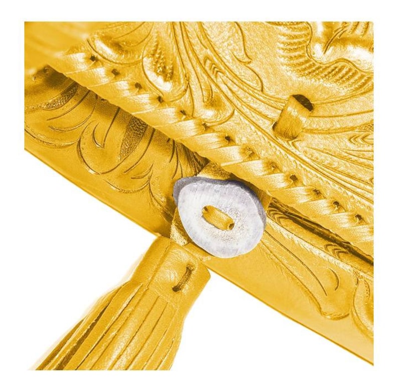 May include: A gold leather wallet with an intricate floral design and a tassel. The wallet has a snap closure and a small, round, white button.