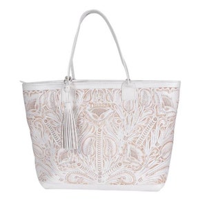 May include: White leather tote bag with a floral embossed design and a tassel. The bag has a zipper closure and a top handle.
