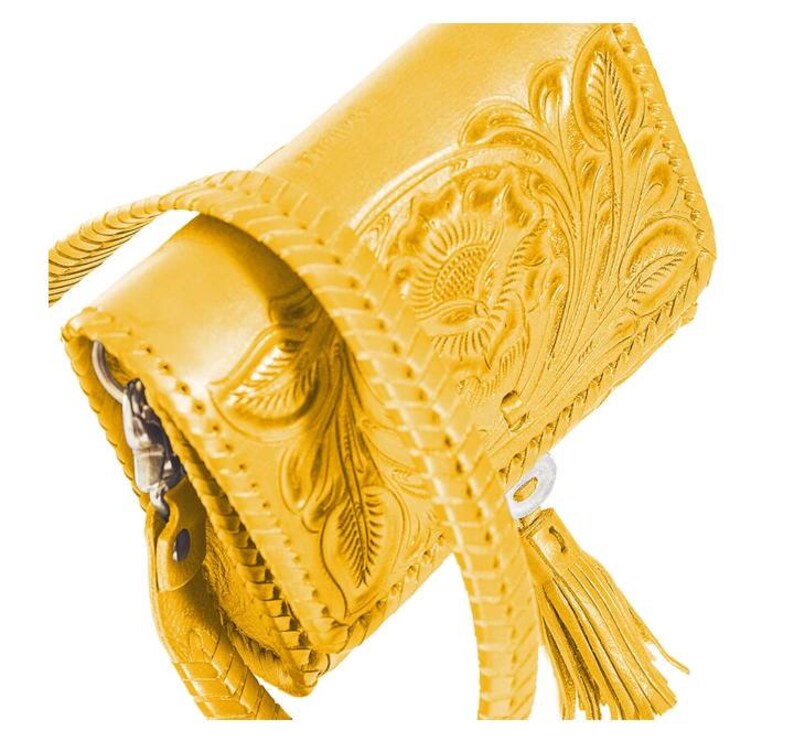 May include: A yellow leather handbag with a floral embossed design and a tassel. The bag has a braided strap and a zipper closure.