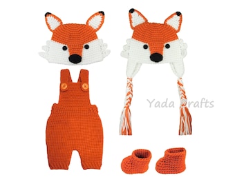 May include: Orange crocheted fox hat, matching overalls, and booties for a baby. The hat has white accents and black eyes and nose. Yada crafts is printed on the image.