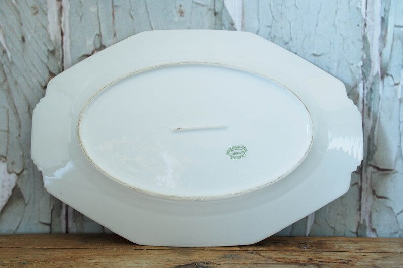 May include: White octagonal serving platter with a green and gold mark on the bottom. The mark reads "Made in France".