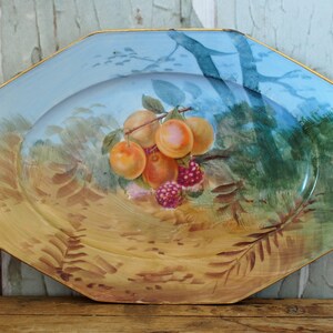 May include: A vintage octagonal ceramic serving platter with a blue and yellow glaze. The platter features a hand-painted design of a branch of fruit with peaches and raspberries.