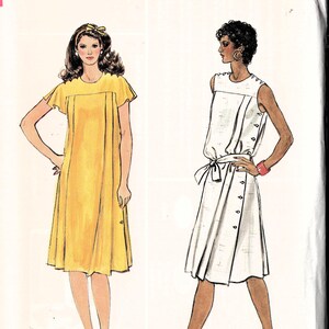 Op de afbeelding: Vogue Patterns naaipatroon met twee jurk ontwerpen. Eén jurk is geel met korte mouwen, de andere is wit met knoopdetails en een strik in de taille. De patroonmaat is 18.