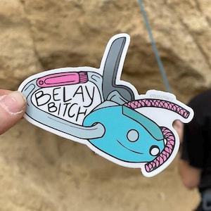 Puede incluir: Una pegatina de un dispositivo de aseguramiento azul con una cuerda rosa y el texto "Belay Bitch".