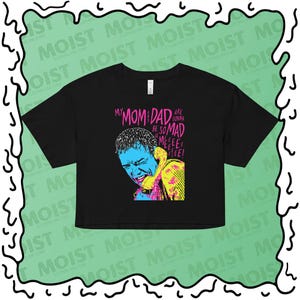 Puede incluir: Top corto negro con un gráfico de una persona al teléfono con acentos azules, amarillos y rosas. El texto dice "MY MOM DAD ARE GONNA BE SO MAD MEEEE EEEE EEEE!"