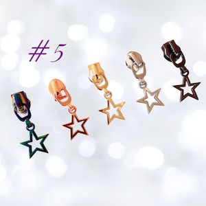 May include: Five zipper pulls with star-shaped charms. The charms are in different colours: rainbow, gold, silver, bronze, and black.