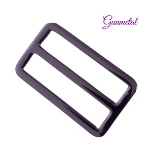 K&ouml;nnte beinhalten: Rechteckige Schiebeschnalle in Gunmetal-Farbe mit zwei parallelen St&auml;ben. Die Schnalle hat eine gl&auml;nzende Oberfl&auml;che und ist vor einem wei&szlig;en Hintergrund platziert. Das Wort "Gunmetal" ist kursiv geschrieben.