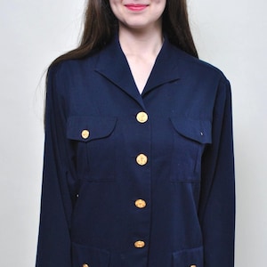 May include: A navy blue blazer with gold-colored buttons and two front pockets. The long-sleeved jacket has a classic collar and a tailored fit. The blazer is a versatile piece of clothing.