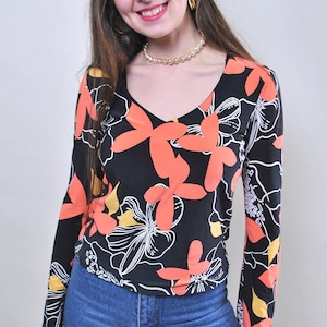 May include: A set of three ceramic mugs with a speckled, cream-colored glaze. Each mug features a different hand-painted design: a blue and green leaf, a yellow flower, and a red berry. The mugs have a simple, rounded shape and a comfortable handle.