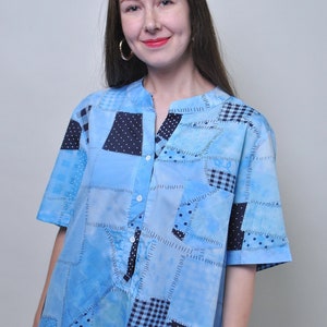 Op de afbeelding: Een blauw en wit patchwork overhemd met knopen en korte mouwen. Het overhemd heeft verschillende patronen, waaronder stippen, ruitjes en paisley.