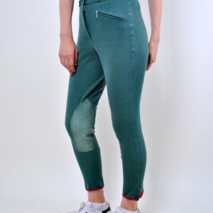 May include: Green riding pants with knee patches and red trim at the bottom. The pants are worn with white sneakers with black stripes.