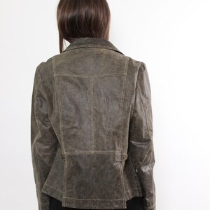 Puede incluir: Chaqueta de cuero verde oliva con cuello cl&aacute;sico y cierre de botones. La chaqueta tiene un corte entallado y costuras detalladas. La vista trasera muestra un dise&ntilde;o estructurado, perfecto para un look retro o atrevido. Prenda exterior elegante.