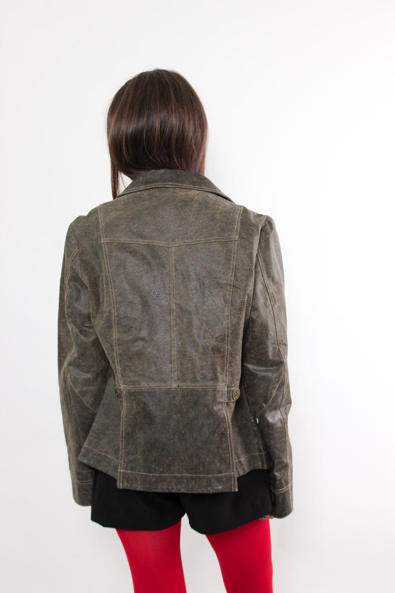 Puede incluir: Chaqueta de cuero verde oliva con cuello cl&aacute;sico y cierre de botones. La chaqueta tiene un corte entallado y costuras detalladas. La vista trasera muestra un dise&ntilde;o estructurado, perfecto para un look retro o atrevido. Prenda exterior elegante.