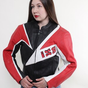 May include: A black leather motorcycle jacket with red and white accents. The jacket has a zipper closure and a large "ISS" logo on the back.
