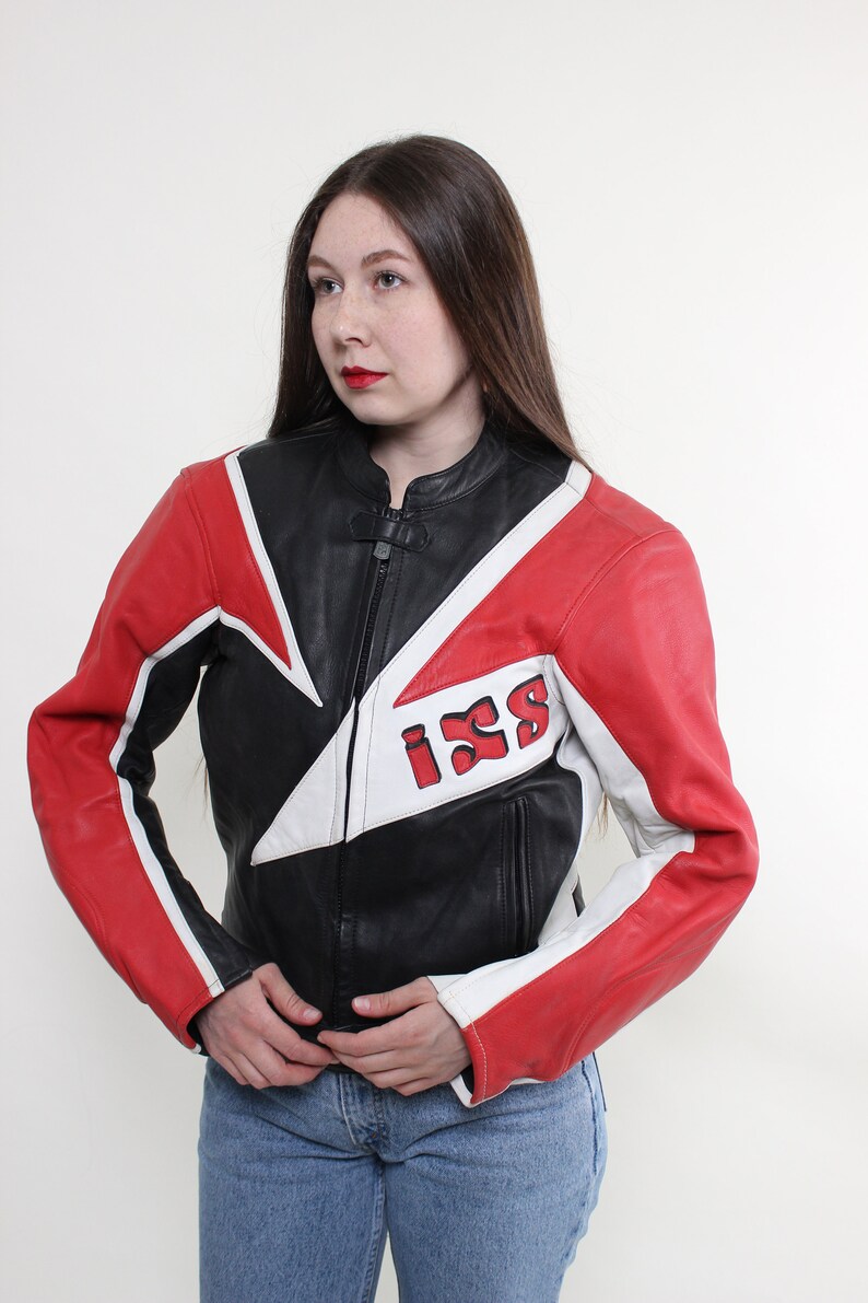 May include: A black leather motorcycle jacket with red and white accents. The jacket has a zipper closure and a large "ISS" logo on the back.