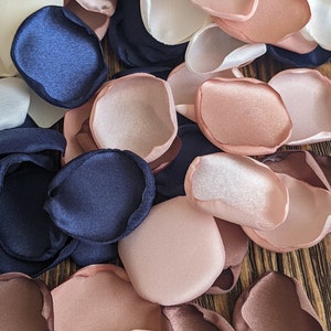 May include: Assortment of fabric flower petals in navy blue, blush pink, ivory white, and brown. The petals are made of satin and are perfect for wedding decorations or crafting projects.