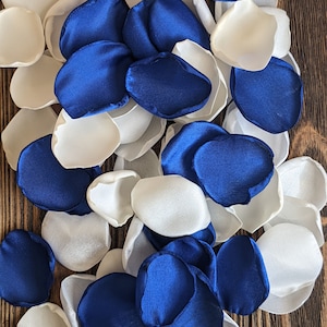 May include: A pile of blue and white satin rose petals. The petals are arranged in a random pattern and are perfect for wedding decorations or other special events.