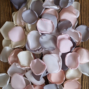 Könnte beinhalten: Ein Haufen Stoffrosenblätter in den Farben Rosa, Weiß und Grau. Die Blütenblätter sind aus Satin und eignen sich perfekt für Hochzeitsdekorationen oder andere besondere Anlässe.