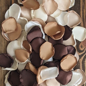 Puede incluir: Un montón de pétalos de flores de seda de color marrón, beige y blanco. Los pétalos están dispuestos en un patrón aleatorio y todos son del mismo tamaño y forma.