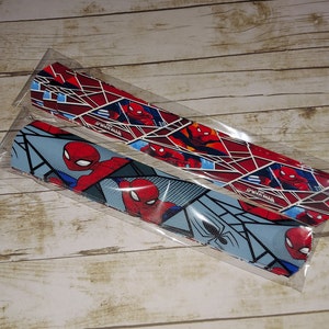 Peut inclure: Deux bandes de tissu sur le th&egrave;me de Spiderman. Une bande est rouge et bleue avec un motif de toile d'araign&eacute;e, tandis que l'autre est bleue et blanche avec un motif de toile d'araign&eacute;e.