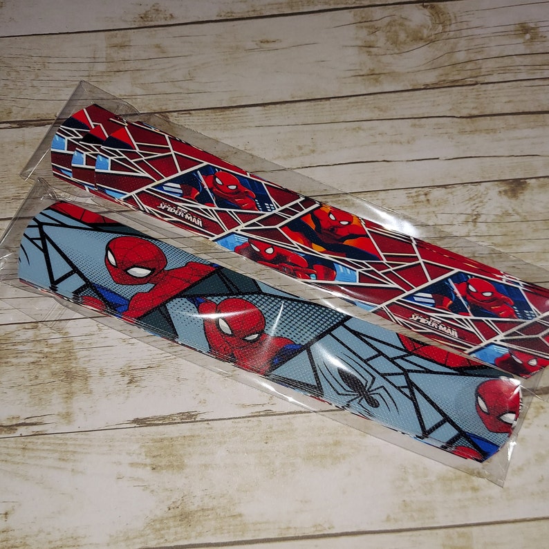 Peut inclure: Deux bandes de tissu sur le th&egrave;me de Spiderman. Une bande est rouge et bleue avec un motif de toile d'araign&eacute;e, tandis que l'autre est bleue et blanche avec un motif de toile d'araign&eacute;e.