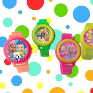 Peut inclure: Quatre montres en plastique colorées avec des personnages de dessins animés de la série télévisée Bubble Guppies. Les montres ont des bracelets de différentes couleurs : rose, vert, jaune et orange. Chaque montre présente une image différente des personnages de Bubble Guppies.