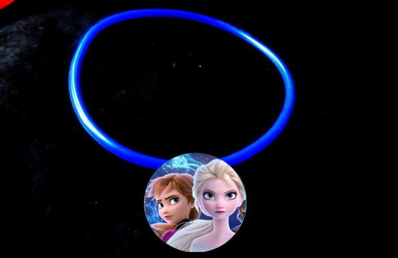 May include: A blue glow stick necklace with a round pendant featuring a picture of Elsa and Anna from the movie Frozen.