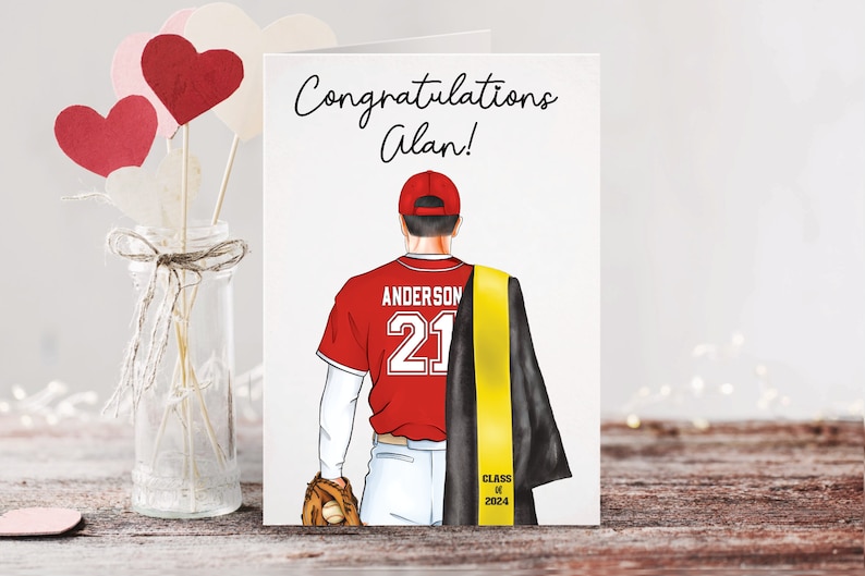 May include: Congratulations Alan! A red and white baseball jersey with the name Anderson and the number 21 on the back. The jersey is worn by a person wearing a black graduation gown with a yellow sash that says "Class of 2024".