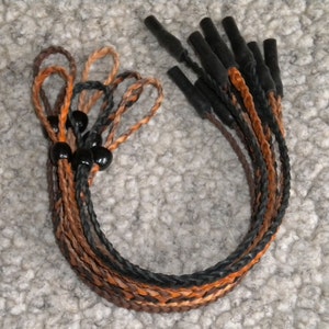 May include: A set of eight braided leather eyeglass retainers with black beads. The retainers are in shades of brown, orange, and black.