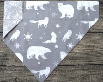 May include: Gray cotton dog bandana with a white snowflake and arctic animal print. The bandana features polar bears, owls, foxes, and snowflakes.