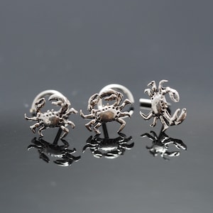 May include: Three silver crab nose rings. The crab designs are detailed and realistic.