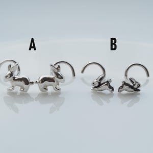 K&ouml;nnte beinhalten: Zwei Paar silberne Nasenringe mit einem Hasendesign. Der Hase links steht und der Hase rechts rennt.