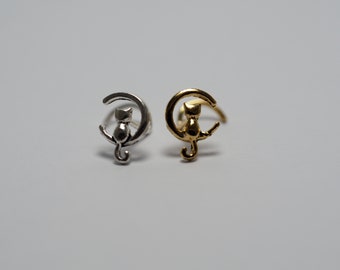 May include: Two cat nose rings, one silver and one gold, with a cat sitting on a crescent moon design.